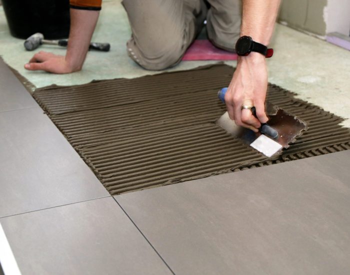 Worker laying floor tiles Worker laying floor tiles